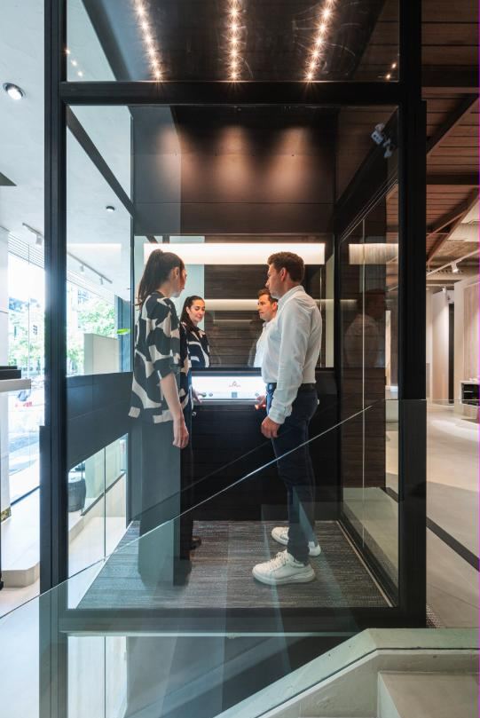 Drie mensen in een ruime glazen lift