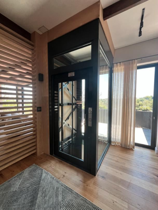 Huislift met glaspanelen naast een terrasraam